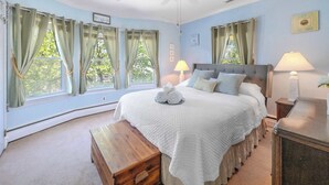 Ein Schlafzimmer mit einem großen Bett, zwei Nachttischlampen, einer Holzbank und einem Deckenventilator.