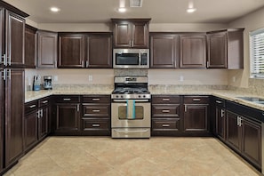 A modern kitchen with dark wood cabinets, stainless steel appliances, and a granite countertop. - Private Courtyard with Hot Tub, Fire & Red Rocks Views (Sedona)