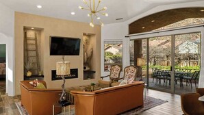 A modern living room with a fireplace, comfortable seating, and a large TV. - Myrinn| Yard w/ Hot Tub, Fire Pit & Red Rock Views (Sedona)