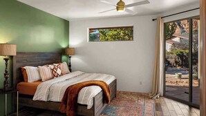 A bedroom with a bed, a ceiling fan, a window with a view, and a door leading to an outdoor area. - Myrinn| Yard w/ Hot Tub, Fire Pit & Red Rock Views (Sedona)