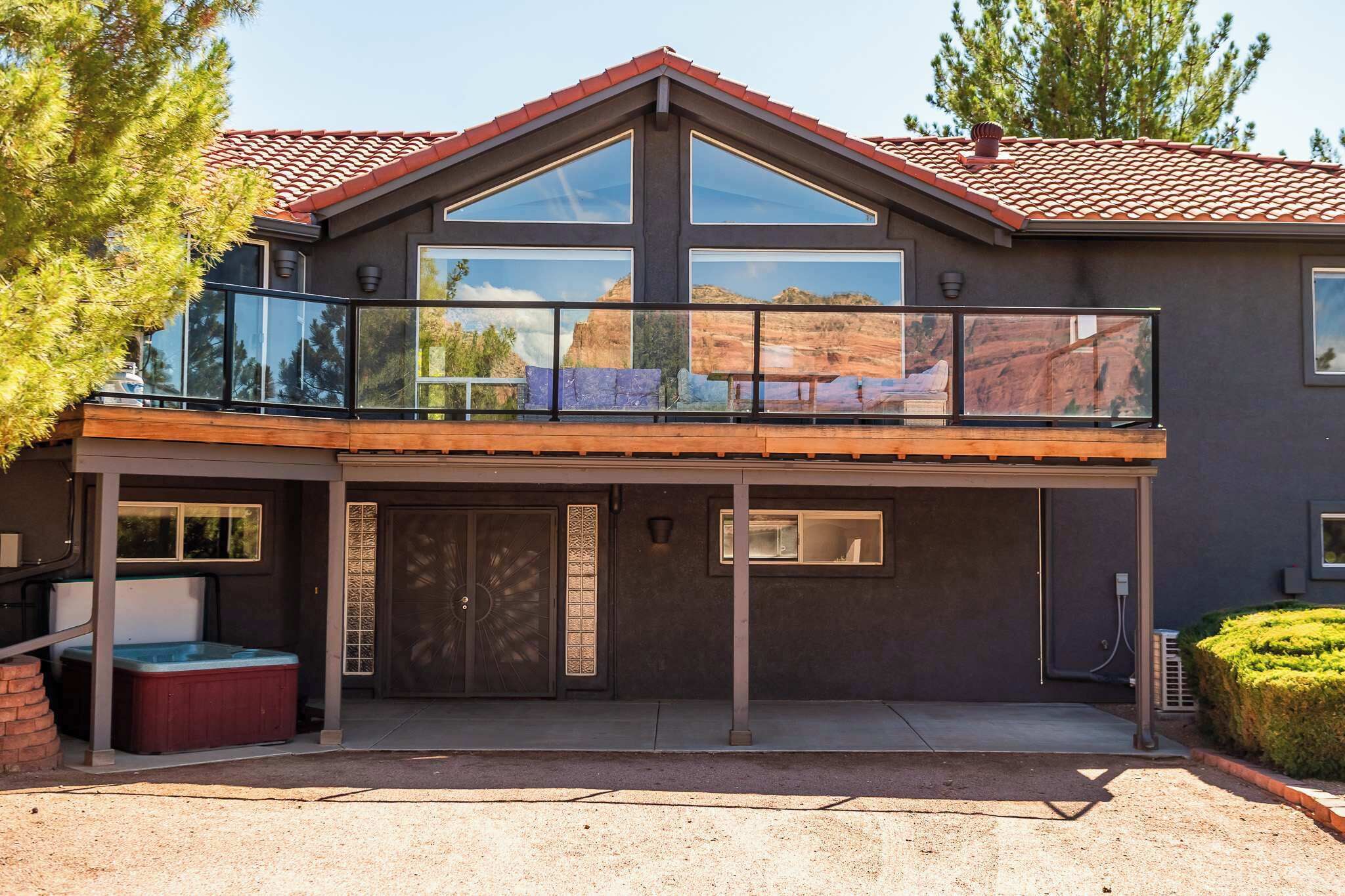 A two-story house with a balcony, large windows, and a hot tub.