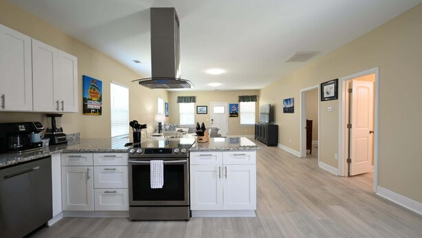 Une cuisine moderne avec des armoires blanches, une cuisinière en acier inoxydable et un îlot central.
