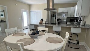 Une cuisine moderne avec des armoires blanches, une hotte de cuisinière en acier inoxydable et un bar pour prendre le petit-déjeuner.