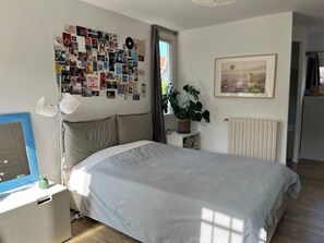 A bedroom with a bed, a wall collage, a plant, a radiator, and a framed picture. - Charming villa with swimming pool in a quiet area close to the sea (Toulon)