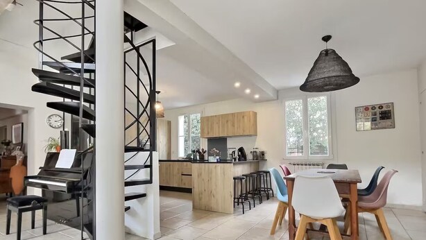 Une cuisine moderne dotée d’un îlot central, de meubles en bois et d’un coin repas avec des chaises aux couleurs vives.