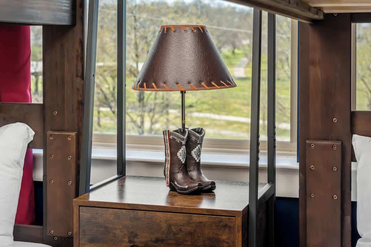Una mesita de noche de madera con una lámpara y un par de botas.