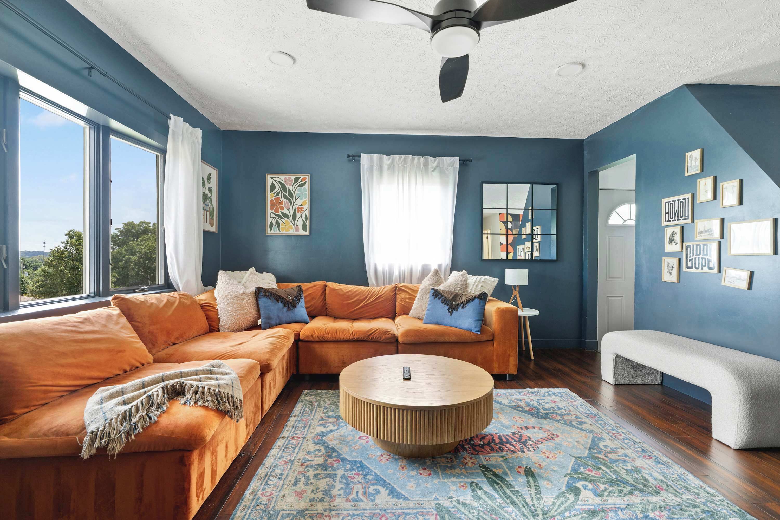 A modern living room with a sectional sofa, a round coffee table, and a large window.