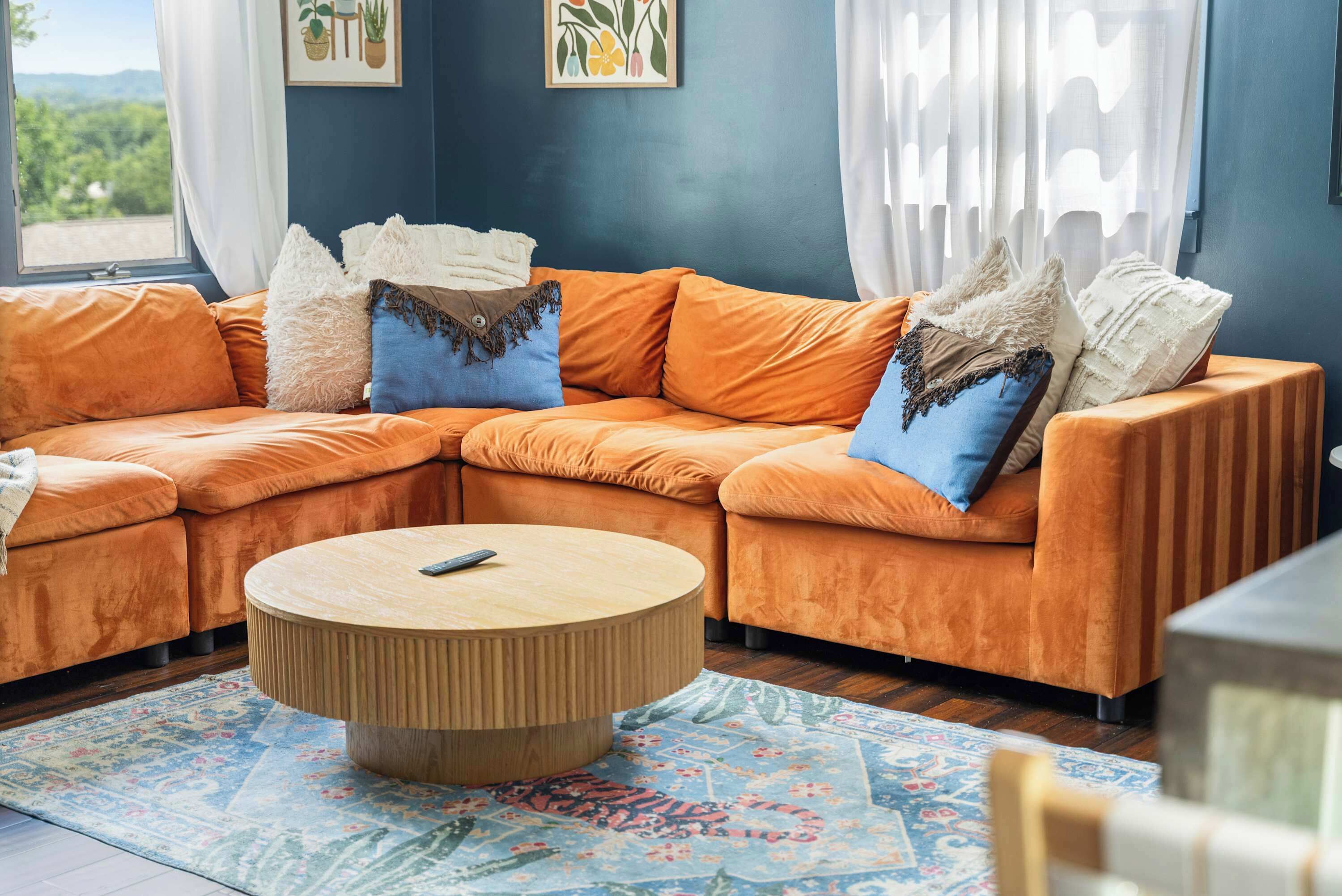 A living room with a sectional sofa, a round coffee table, and a patterned rug.