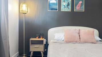 A bedroom with a bed, bedside table, lamp, and wall art.
