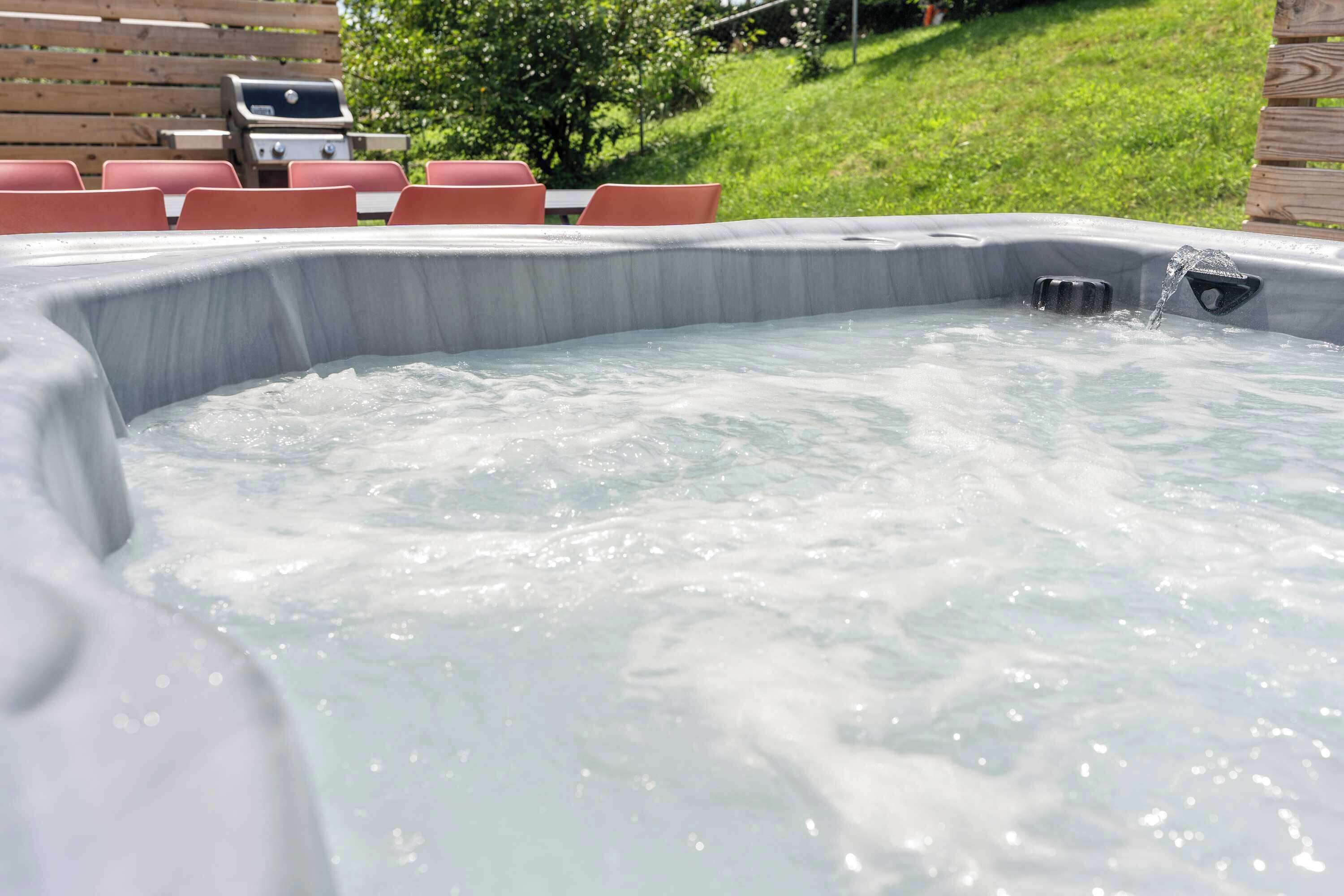 A hot tub with water jets, surrounded by a wooden deck and red chairs.