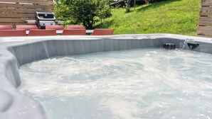 A hot tub with water jets, surrounded by a wooden deck and red chairs. - Fun Midcentury Home | Hot Tub | Karaoke | Games (Lancaster)