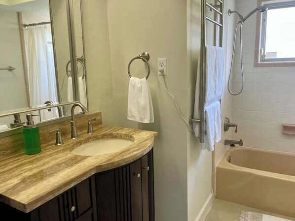 A bathroom with a double sink, a mirror, a towel ring, and a bathtub.