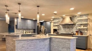 A modern kitchen with a curved island, stainless steel appliances, and pendant lighting.