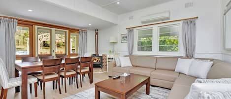 Ein geräumiges Wohnzimmer mit einer Couch, einem Couchtisch und einem Essbereich mit Stühlen.