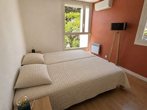 Ein Schlafzimmer mit Bett, Nachttisch, Lampe und Fenster.