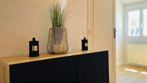 A room with a wooden console table, a woven basket vase with green plants, and two black candle holders. - La Maison d Utah , Beach and Memory (Sainte-Marie-du-Mont)