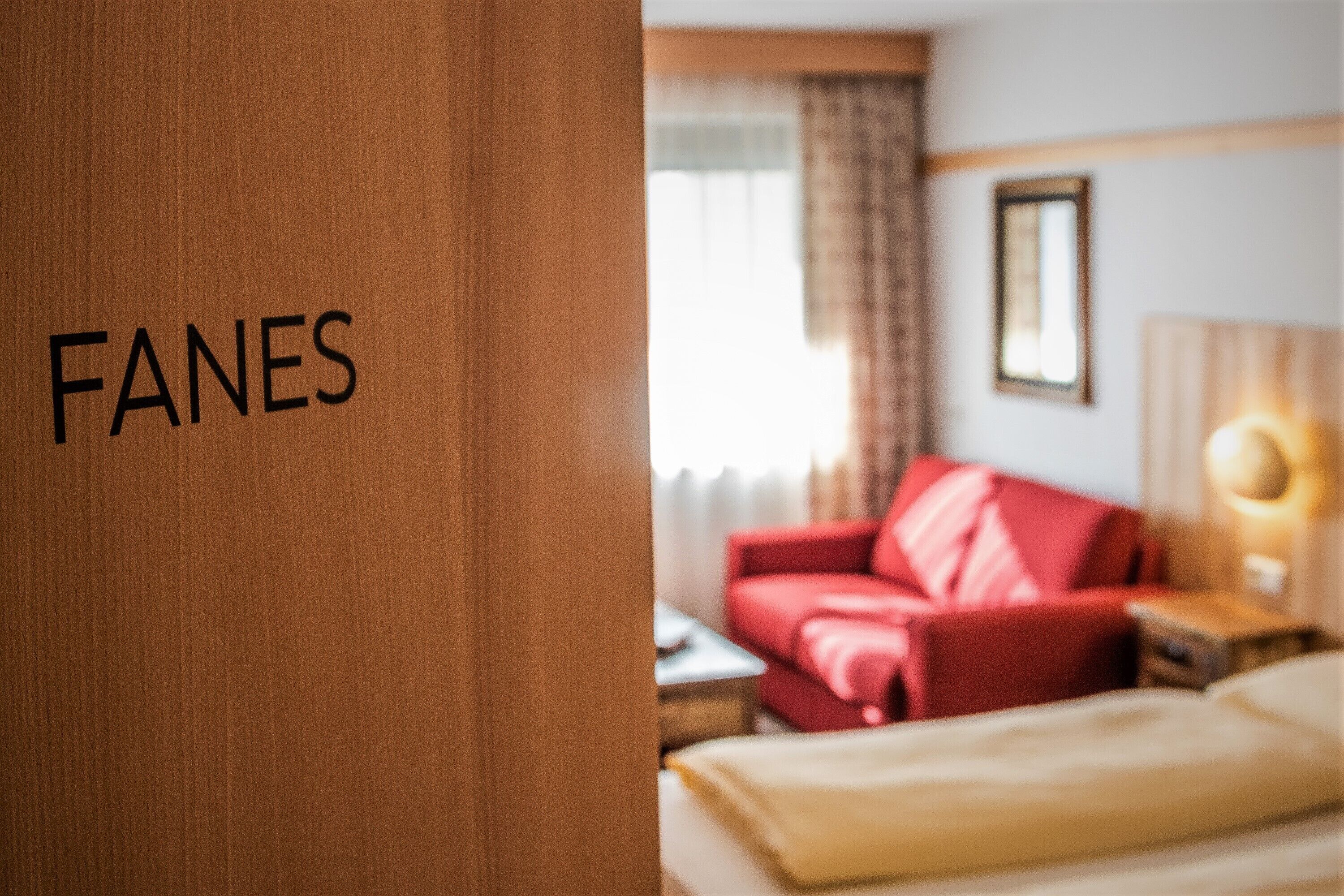 Una habitación de hotel con un sofá rojo, una mesita de noche y una lámpara.