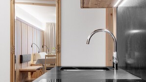 A modern bathroom with a black countertop, a chrome faucet, and a wooden-framed mirror. - Residence Ada (San Cassiano)