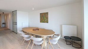 A modern dining area with a round table, six chairs, a whiteboard, and a radiator.