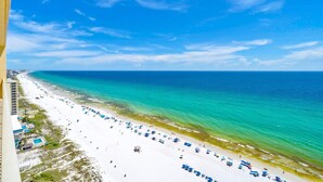 A beach with a clear view of the ocean and a hotel building in the background. - Gulf Crest 2105b (Panama City Beach)