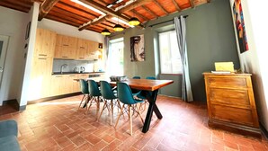 Een ruime keuken met houten kastjes en een eethoek met een tafel en stoelen.