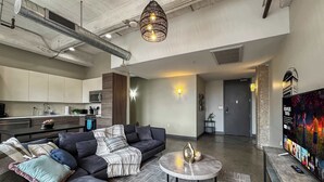 A modern living room with a sectional sofa, a round coffee table, and a kitchen in the background.