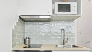A compact kitchen with a washing machine, a microwave, and a sink. - Well-equipped studio near the Parc des Princes (Paris)