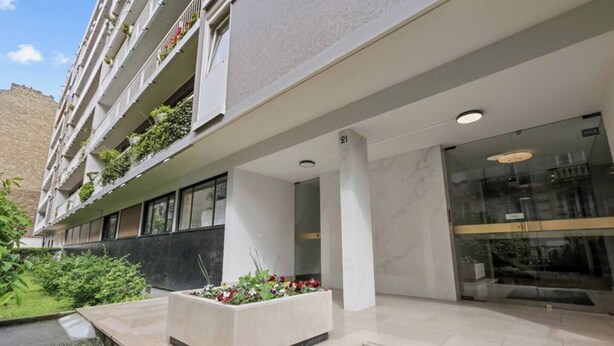 A modern hotel with a clean facade, a central entrance with a marble floor, and a balcony with greenery. - Well-equipped studio near the Parc des Princes (Paris)