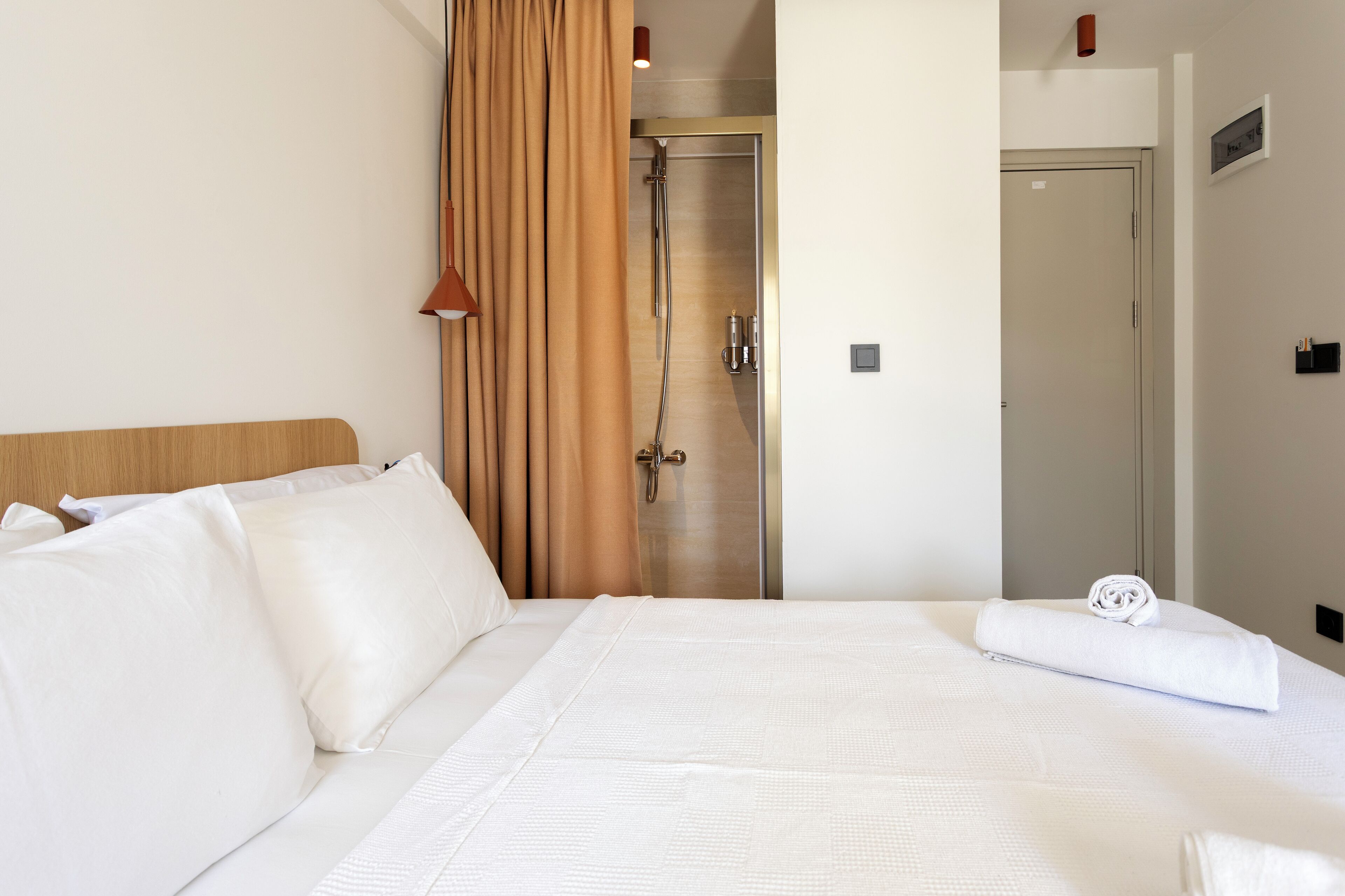 A hotel room with a large bed, a shower area, and a door leading to another room.