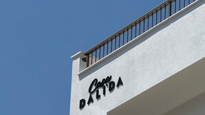Ein Gebäude mit weißer Fassade und einem Balkon mit Metallgeländer.