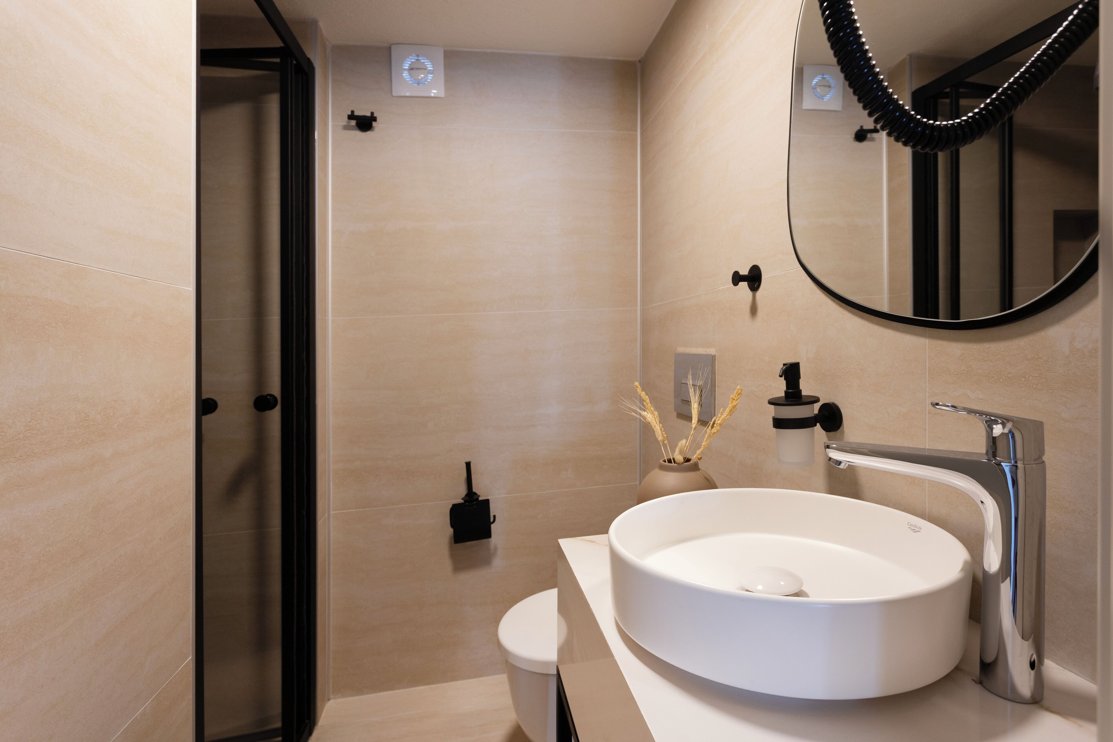 A modern bathroom with a round sink, a toilet, and a glass shower enclosure.