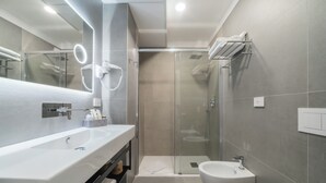 A modern bathroom with a large white sink, a glass-enclosed shower, and a separate white pedestal sink. - Brera Guest House (Milan)