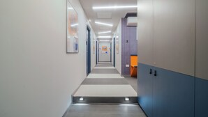 A modern hallway with a tiled floor, blue lockers on one side, and framed pictures on the walls. - Brera Guest House (Milan)
