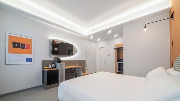 A modern hotel room with a large bed, a desk with a mirror, a wardrobe, and a shower. - Brera Guest House (Milan)