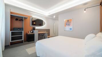Una habitación de hotel moderna con una cama grande, un escritorio con silla, un armario y un baño.