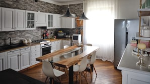 A modern kitchen with white cabinets, a wooden island, and a large refrigerator.