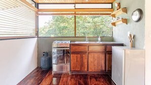 Una cocina compacta con armarios de madera, estufa a gas, lavamanos y refrigerador.