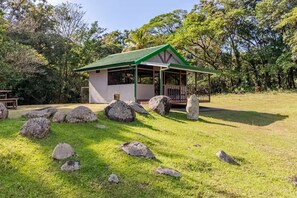 Ein kleines, eingeschossiges Gebäude mit Gründach und Veranda, umgeben von großen Steinen und Gras.