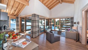 A spacious living area with wooden ceilings, large windows, and a cozy seating arrangement. - 3-room deluxe vacation apartment (Churwalden)