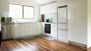 Eine moderne Küche mit weißen Schränken, Edelstahlgeräten und Holzboden.