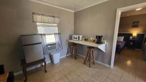 A compact kitchen with a refrigerator, microwave, and bar stools.