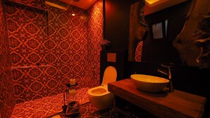 Une salle de bain avec des carreaux décorés, des toilettes, un lavabo et un miroir.