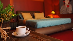 Une chambre d’hôtel avec un lit, une table sur laquelle se trouve une tasse de café, une plante et un tableau accroché au mur.