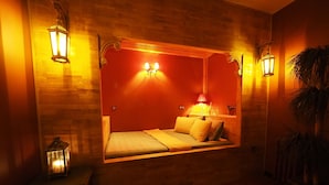 Une chambre confortable avec un lit intégré, deux lampes fixées au mur et une petite table de chevet avec une lampe.