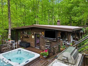 A wooden cabin with a hot tub, deck, and outdoor seating area surrounded by trees. - Modern, Luxurious Cabin for Two located on a Cascading Waterfall. (Jasper)