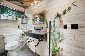 A modern bathroom with a wooden wall, a vintage-style sink, and a toilet. - Modern, Luxurious Cabin for Two located on a Cascading Waterfall. (Jasper)