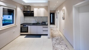 A modern kitchen with a built-in oven, a black countertop, and a window with a view. - Villa Tomi Nature Retreat (Sarajevo)