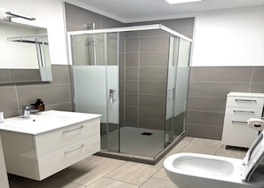 A modern bathroom with a glass shower enclosure, a white sink with a soap dispenser, and a toilet. - Rest and Restaurant in Roveredo (Roveredo)
