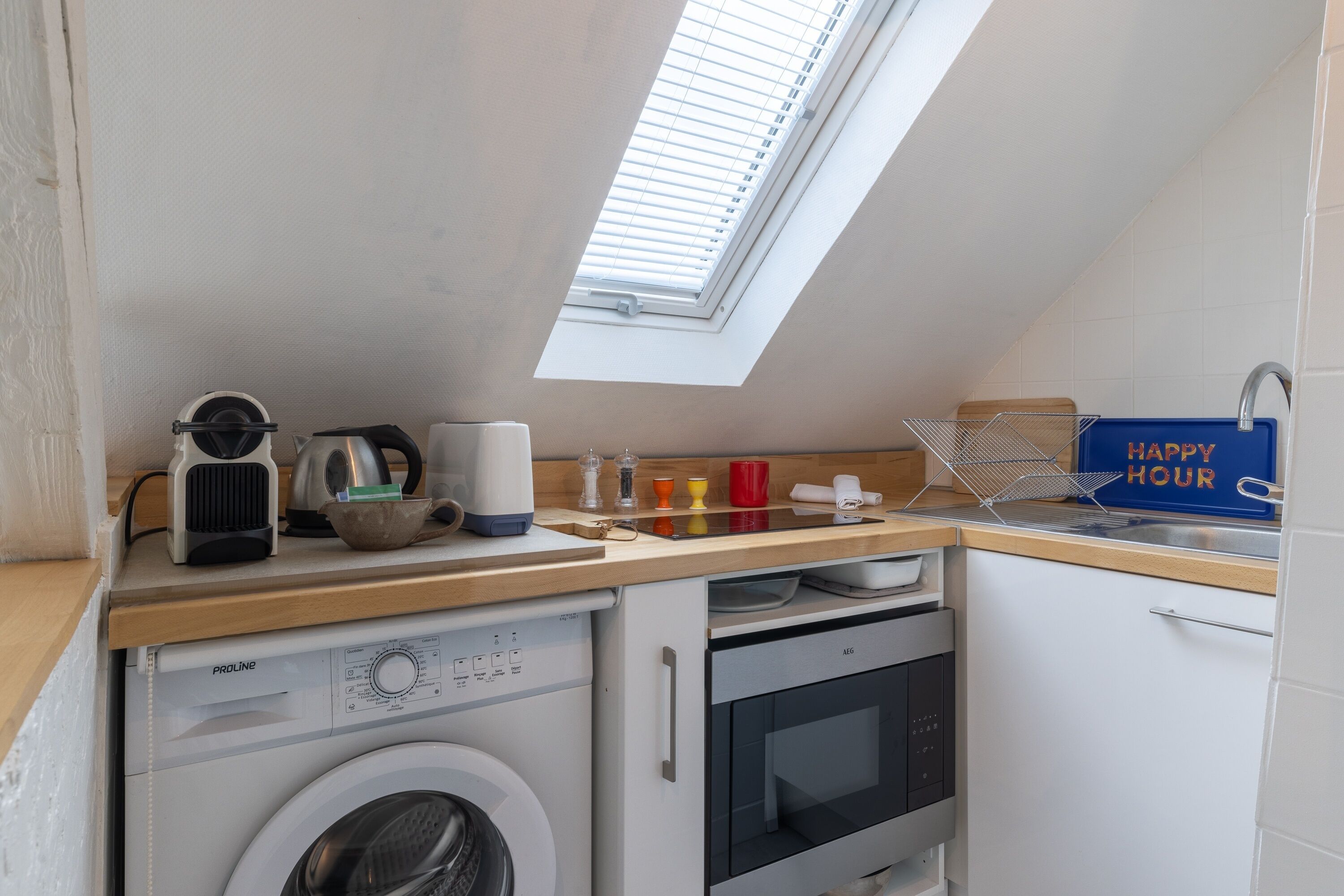 A compact kitchen with a washing machine, oven, and a skylight.