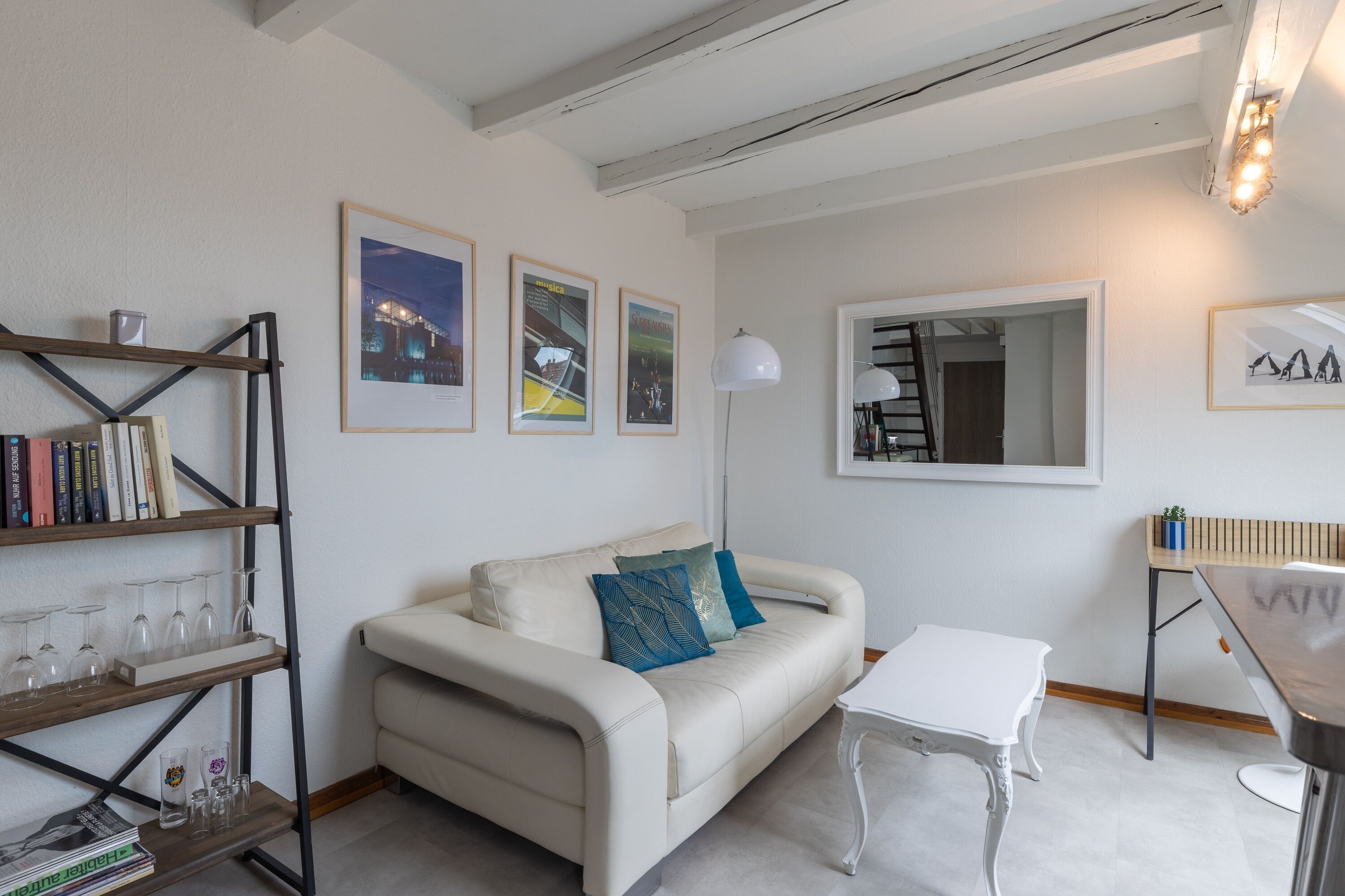 A modern living room with a white sofa, a wooden bookshelf, and a white table.